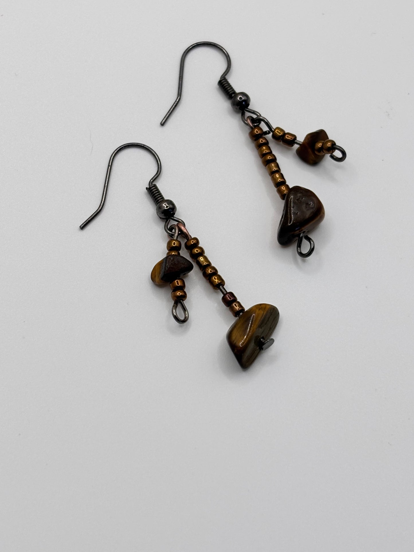 Pair of bronze-colored earrings with heart-shaped stones on a white background