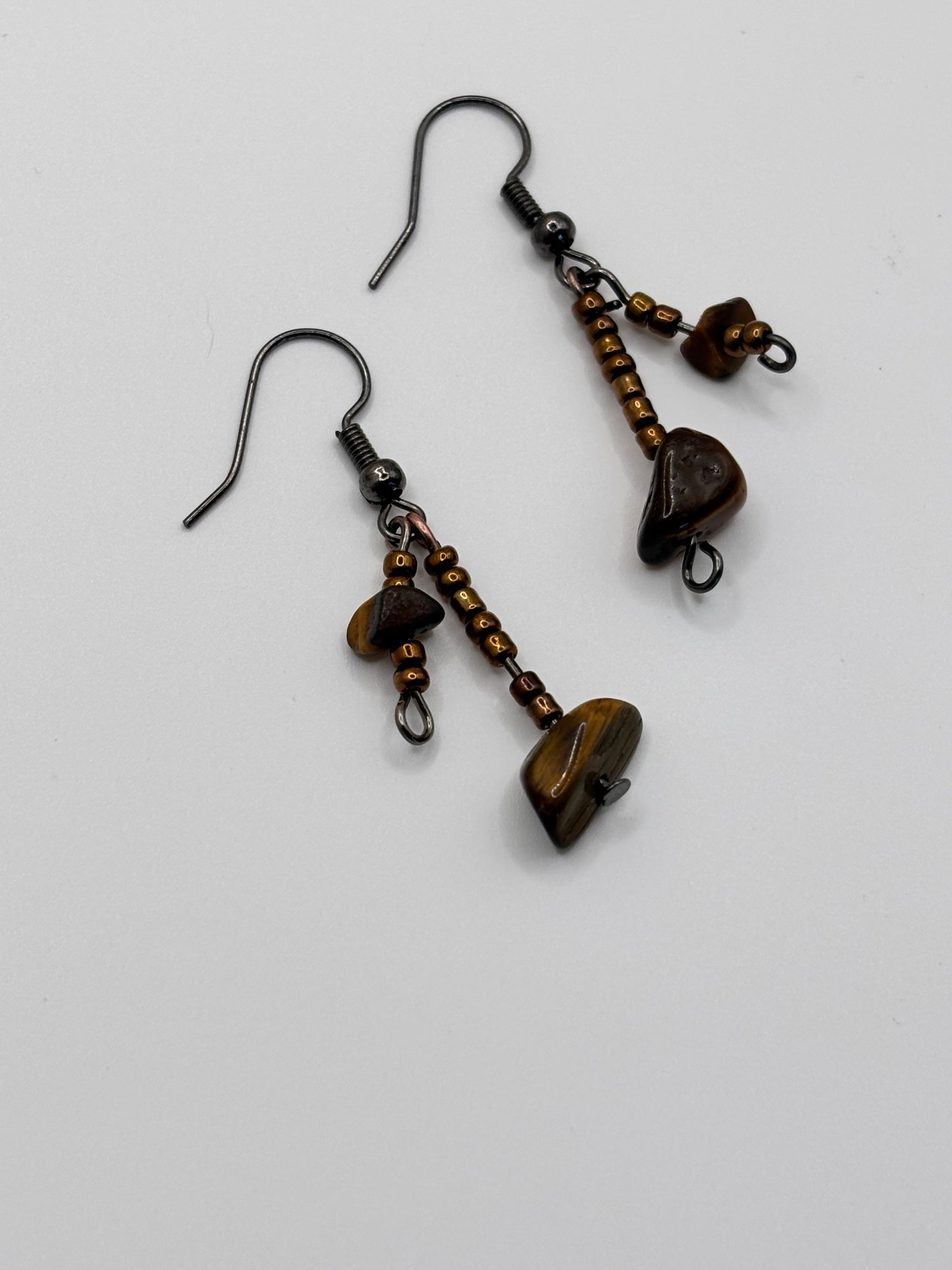 Pair of bronze-colored earrings with heart-shaped stones on a white background