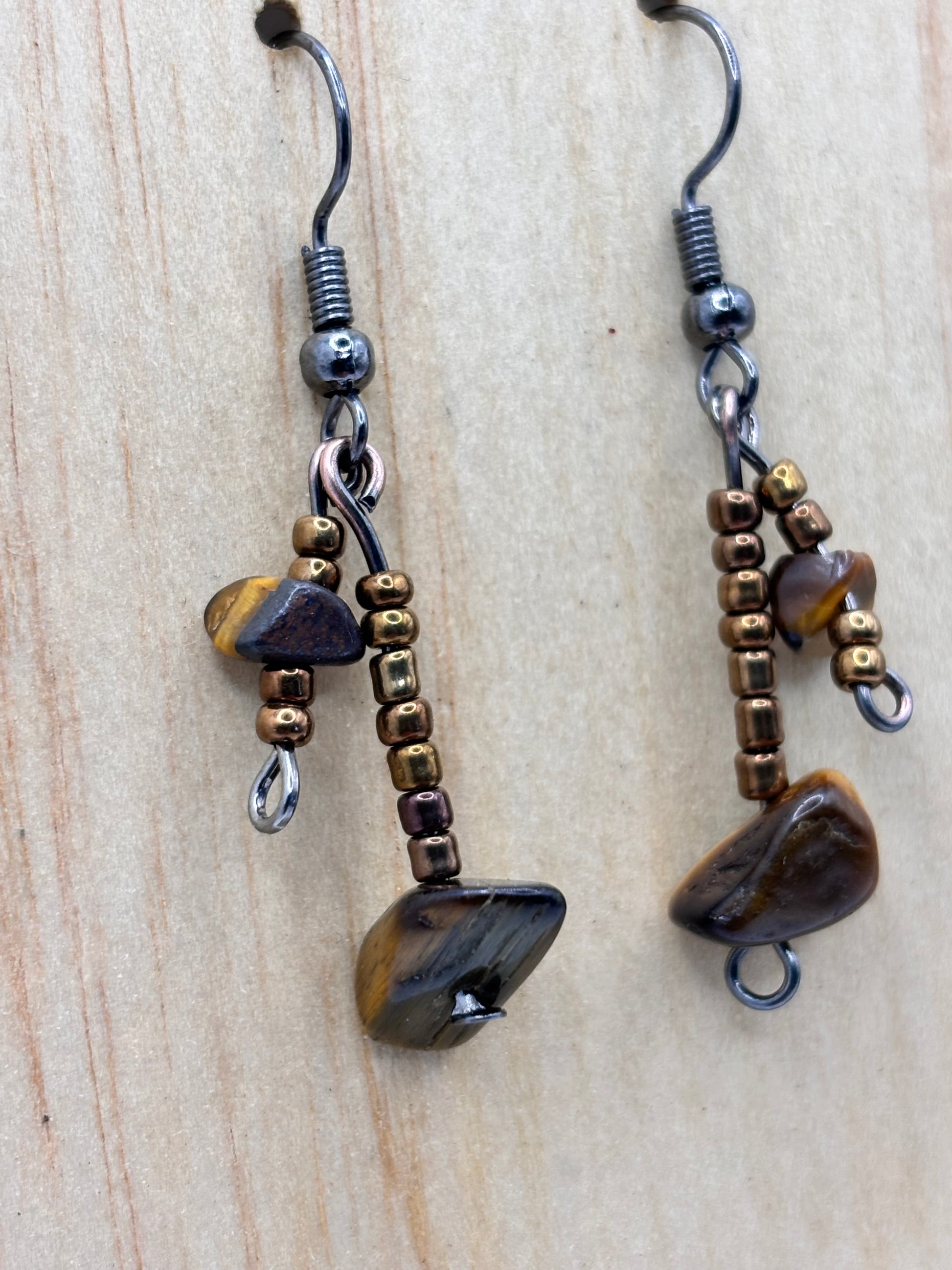 Pair of beaded earrings with natural stone accents on a wooden surface