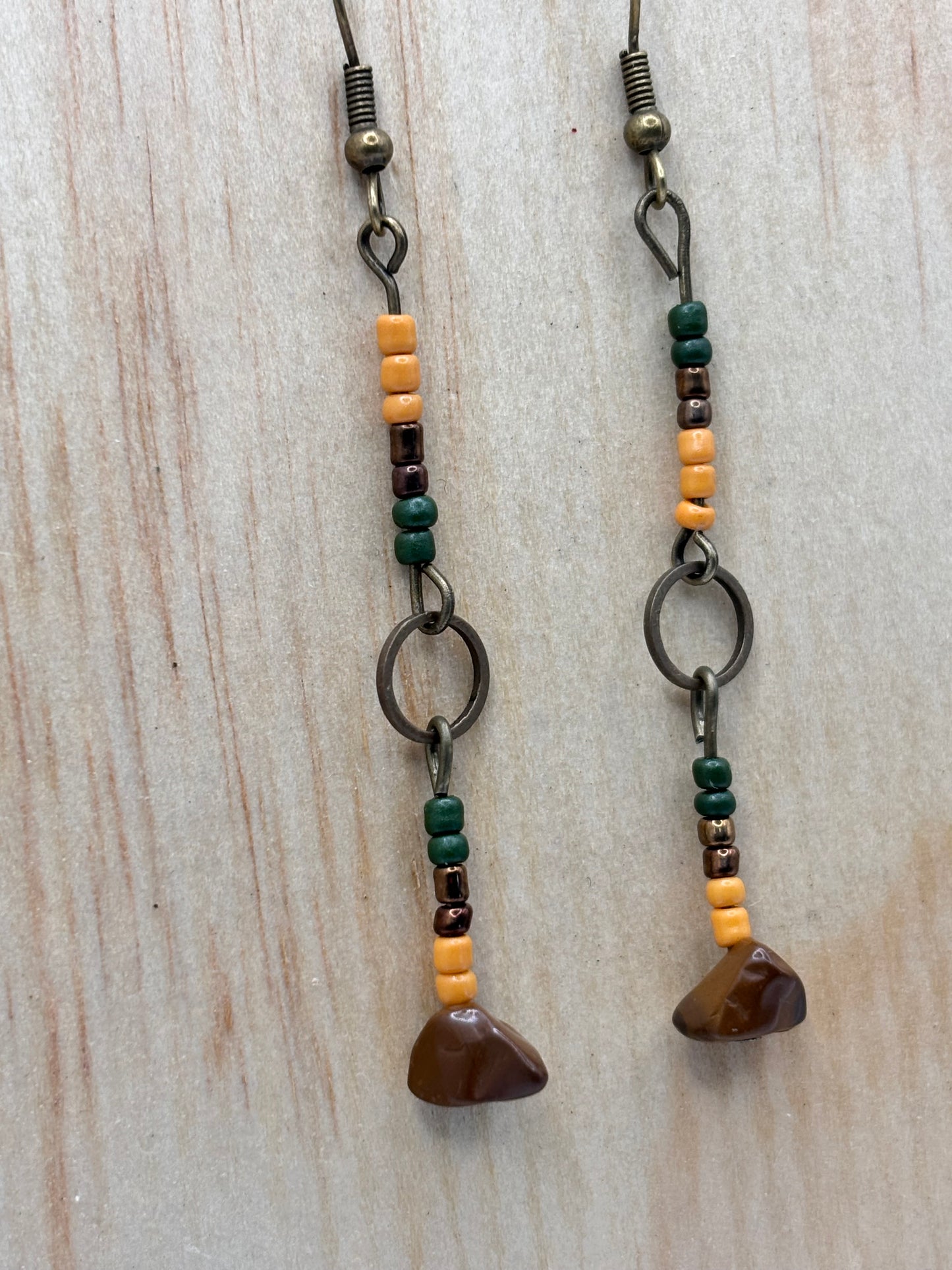Two beaded bracelets with brown stones on a light wooden surface